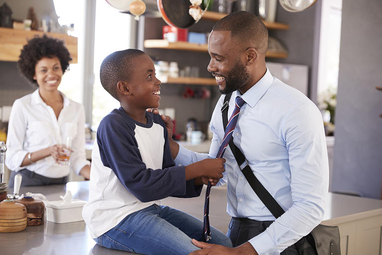 Dad wearing tie with son and mother in kitchen